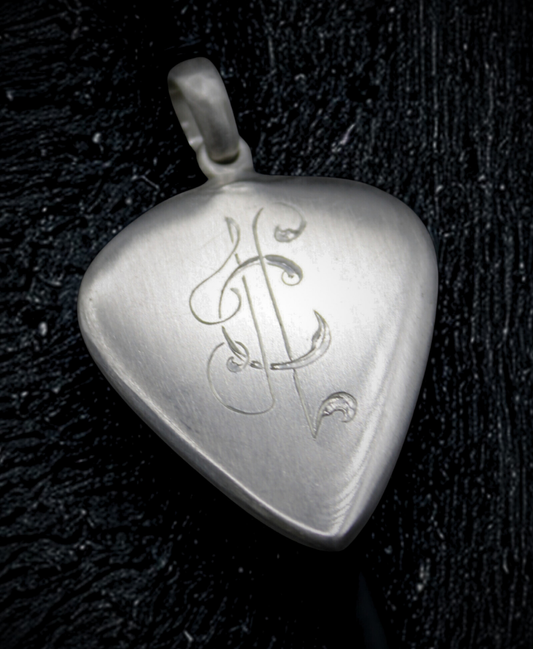 Silver heart-shaped pendant with engraved design on a dark textured background