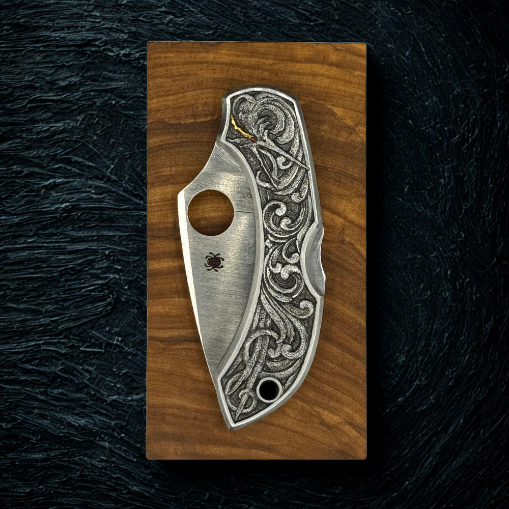 Decorative knife blade with intricate patterns on a wooden block against a dark background