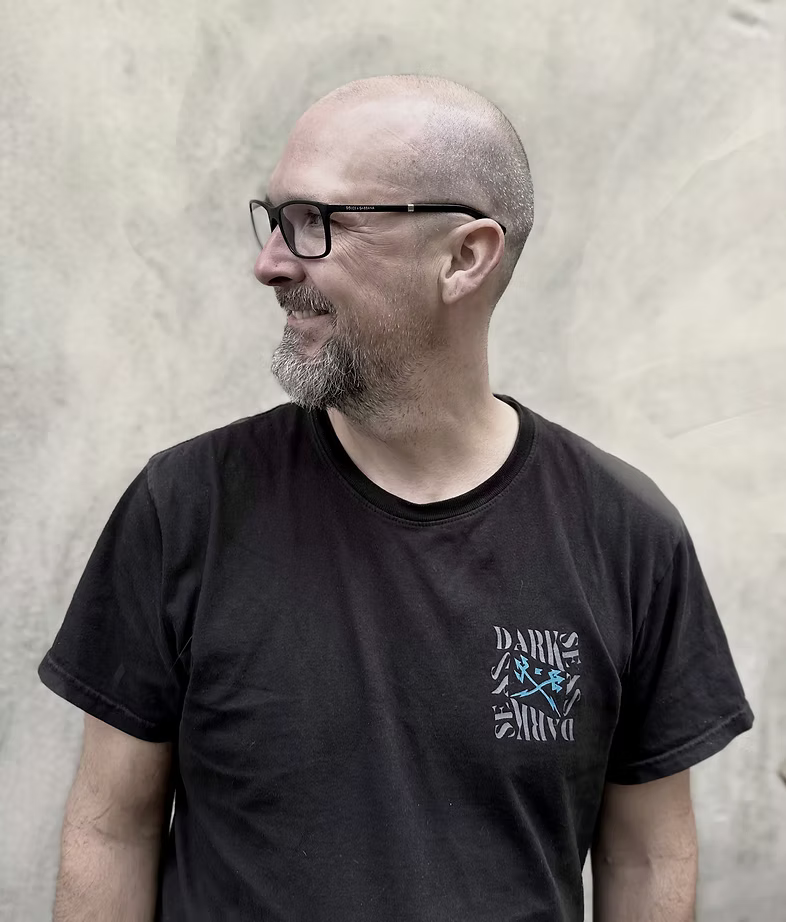 Man wearing a black t-shirt with a logo against a plain background