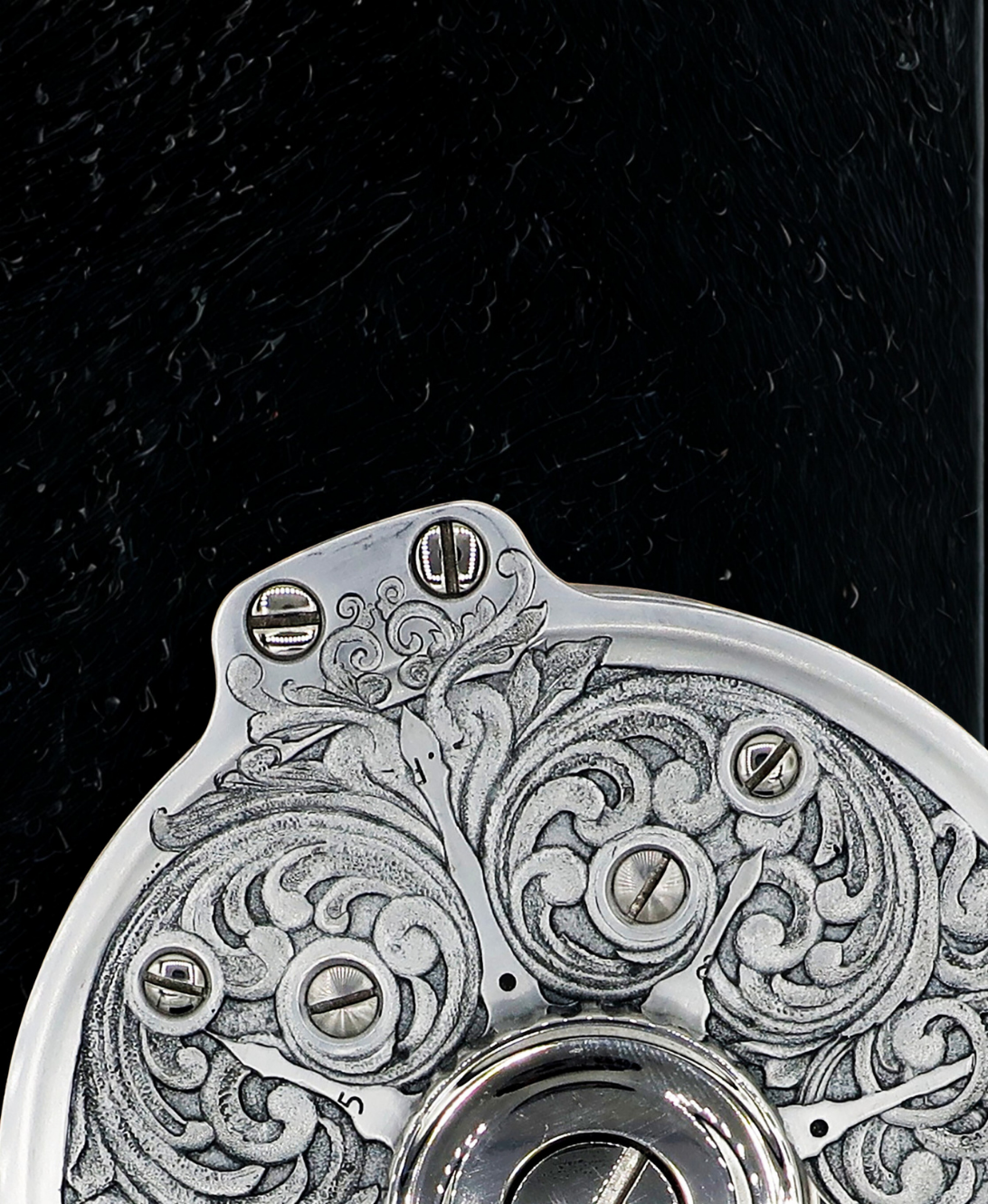 Close up of a Hand engraved salar fly fishing reel by VRDesigns. The engraving features scrollwork. The reel is sitting on a black background